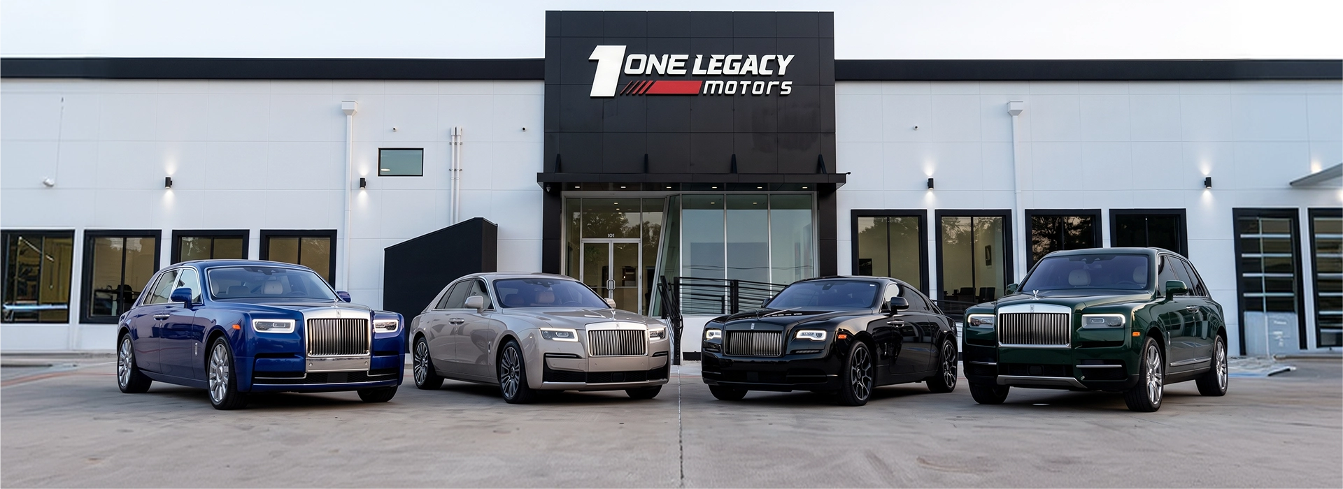 A blue Phantom, a silver Ghost, a black Wraith and a green Cullinan parked in a row outside the One Legacy Motors showroom in Carrollton, Texas