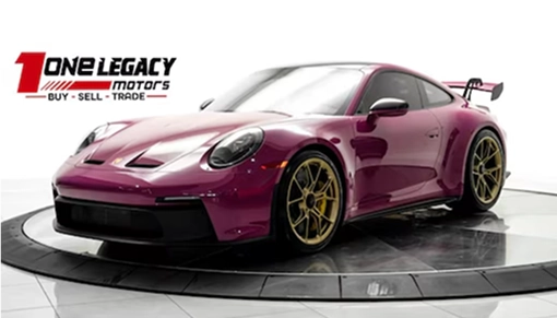 Magenta 2023 Porsche 911 GT3 on gold wheels with a fixed rear wing, photographed on the One Legacy Motors turntable