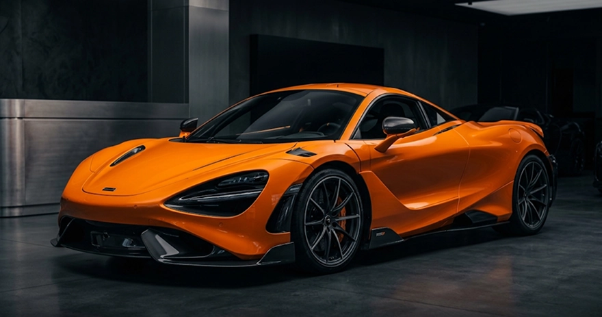 Orange McLaren 720S lit from above on a dark One Legacy Motors showroom floor