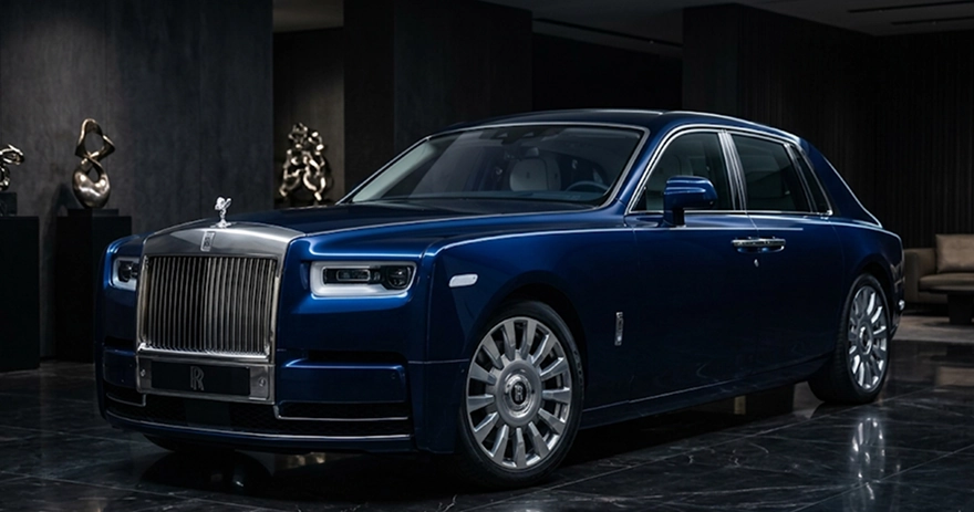 Dark blue Rolls-Royce Phantom in a low-lit showroom with sculptures on plinths behind it
