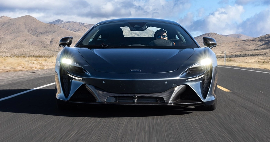 Grey McLaren Artura driving head-on along a desert highway