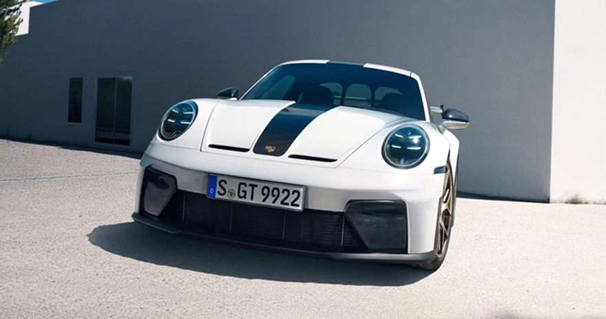 White Porsche 911 GT3 on gold wheels parked in front of a white concrete building