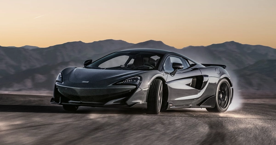 Grey McLaren 600LT cornering hard on a mountain road at sunset