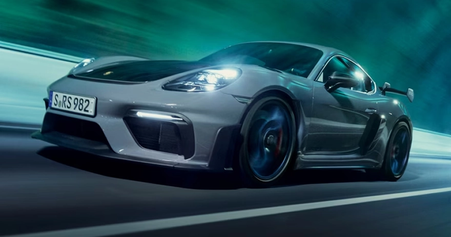Grey Porsche 718 Cayman GT4 RS at speed against a streaking green and blue backdrop