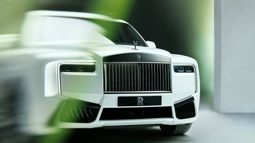 Front three-quarter view of a white Rolls-Royce Cullinan Black Badge with a blacked-out grille