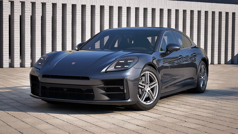 Dark grey Porsche Panamera parked at an angle in front of a ribbed white facade