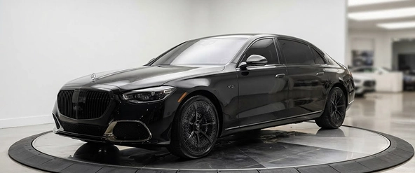 Black Mercedes-Benz GLS seen from the front three-quarter in a dark showroom