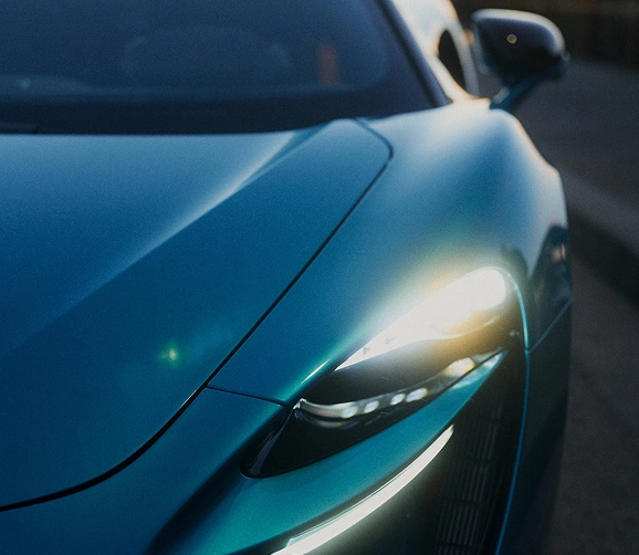 Close-up of a teal McLaren Artura's front wing and slim LED headlight