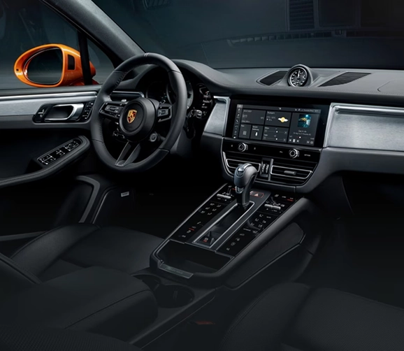 Porsche Macan cockpit with a black leather dashboard, centre touchscreen and an orange wing mirror in view