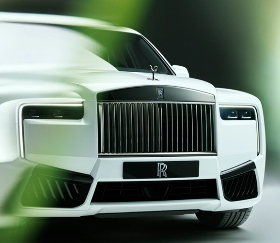 Front three-quarter view of a white Rolls-Royce Cullinan Black Badge, its grille and badge in gloss black