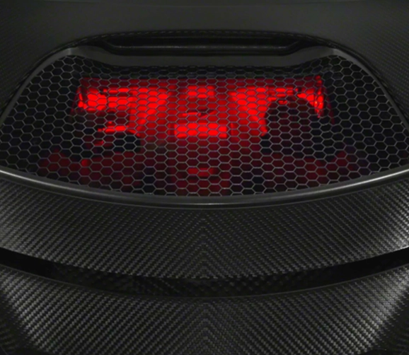Red-lit engine bay of a McLaren 720S seen through its carbon fibre mesh cover