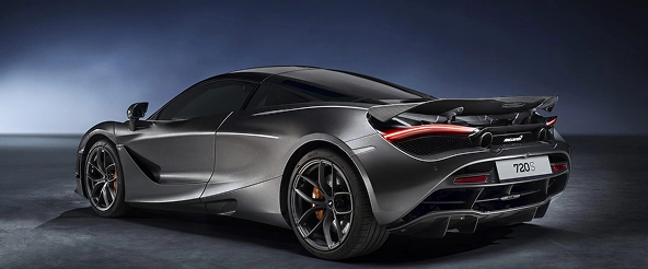 Rear three-quarter of a grey McLaren 720S in a dark studio, showing its active rear wing