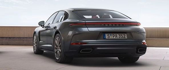Grey Porsche Panamera seen from the rear three-quarter, showing its full-width light bar