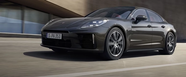 Dark Porsche Panamera driving out from under a concrete canopy