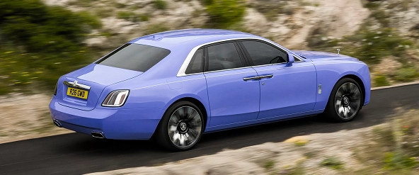 Lilac Rolls-Royce Ghost seen from the rear three-quarter on a mountain road
