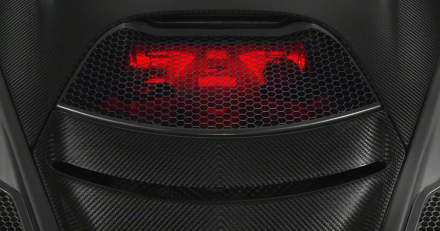Red-lit engine bay of a McLaren 720S seen through its carbon fibre mesh cover