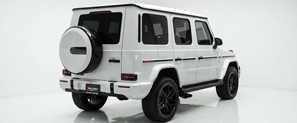 Rear three-quarter view of a white Mercedes-AMG G 63 with its tailgate-mounted spare wheel