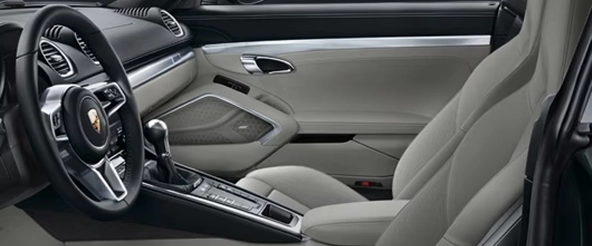 Porsche 718 Cayman interior with a black leather steering wheel, PDK selector and light grey seats