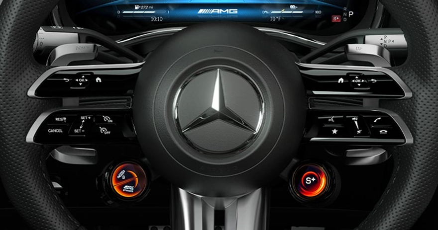 Mercedes-AMG steering wheel with the drive-mode dials and the AMG cluster behind it