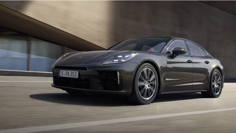 Dark grey Porsche Panamera on the move in front of a curved concrete building