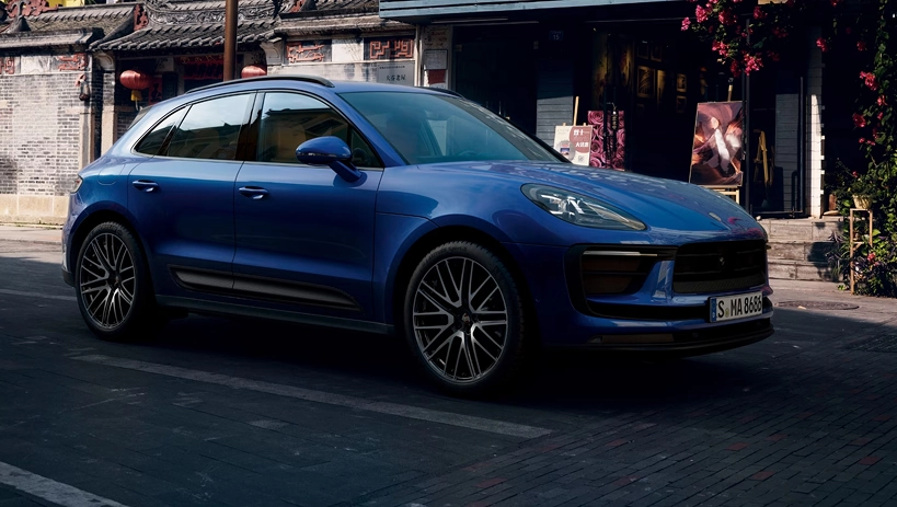 Blue Porsche Macan parked on a street lined with traditional shopfronts