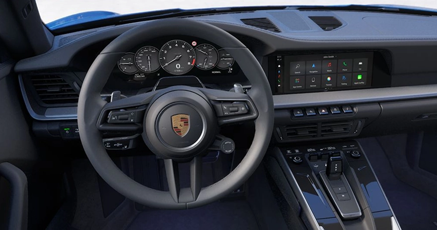 Porsche 911 cockpit with the Porsche-crest steering wheel, analogue rev counter and centre touchscreen