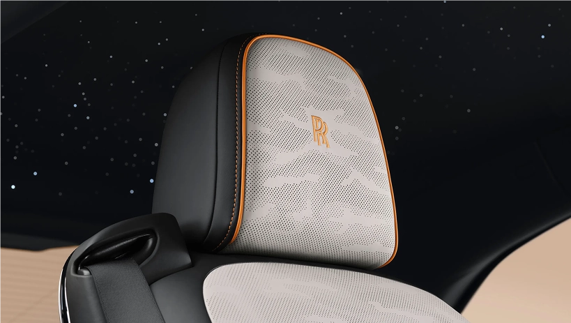 Rolls-Royce Spectre headrest in pale perforated leather with the RR monogram, under a starlight headliner