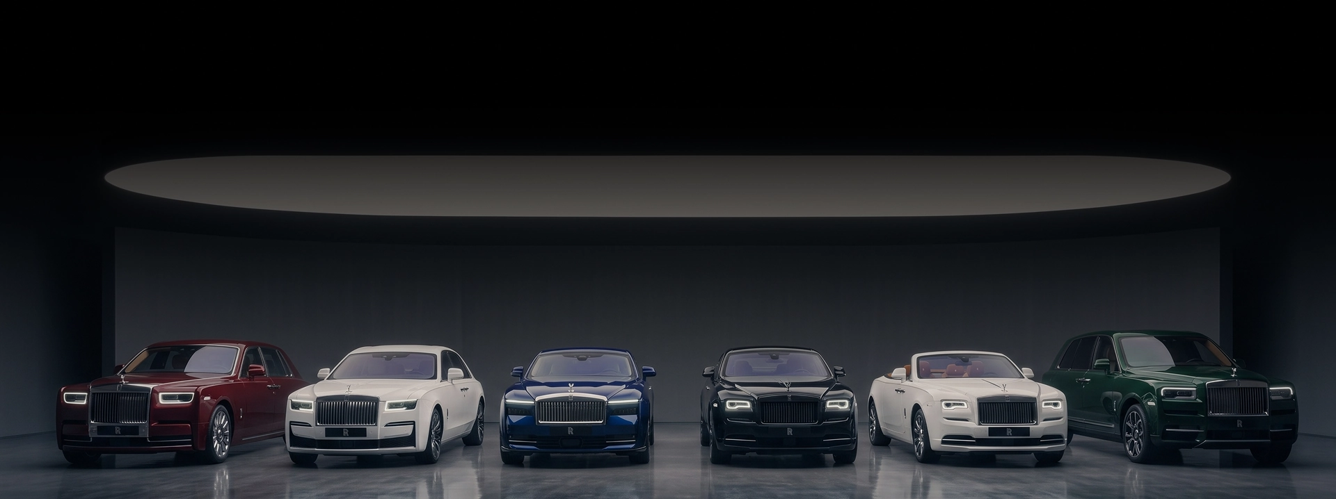 A red Phantom, a white Ghost, a blue Dawn, a black Wraith, a white Dawn and a green Cullinan lined up in a dark studio