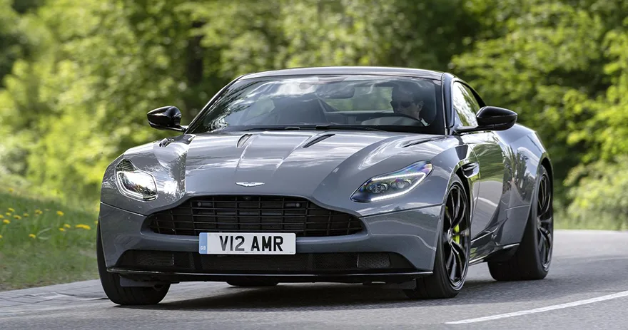 Grey Aston Martin DB11 driving along a tree-lined country road
