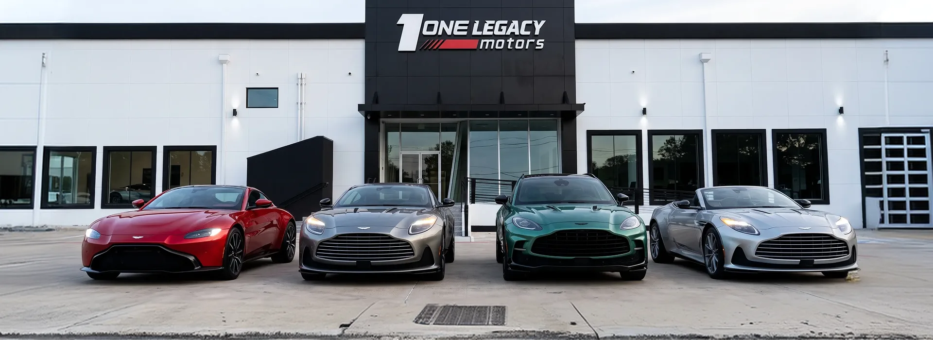 Red, grey, green and dark Aston Martins parked side by side outside the One Legacy Motors showroom in Carrollton, Texas