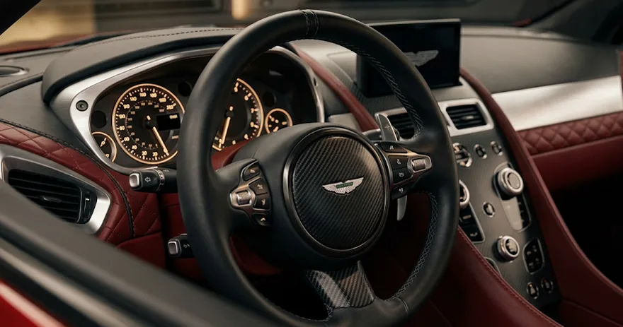 Close-up of an Aston Martin steering wheel and red leather cockpit
