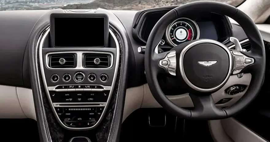 Aston Martin DB11 cabin with its dashboard, steering wheel and cream leather trim