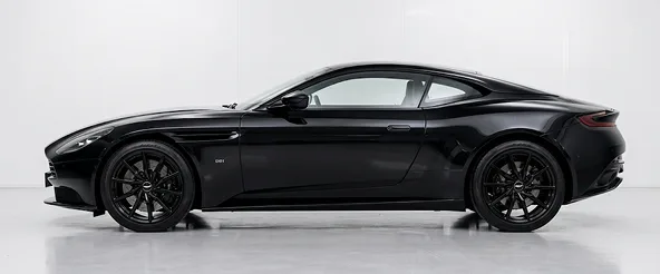 Black Aston Martin DB11 in profile against a pale studio backdrop