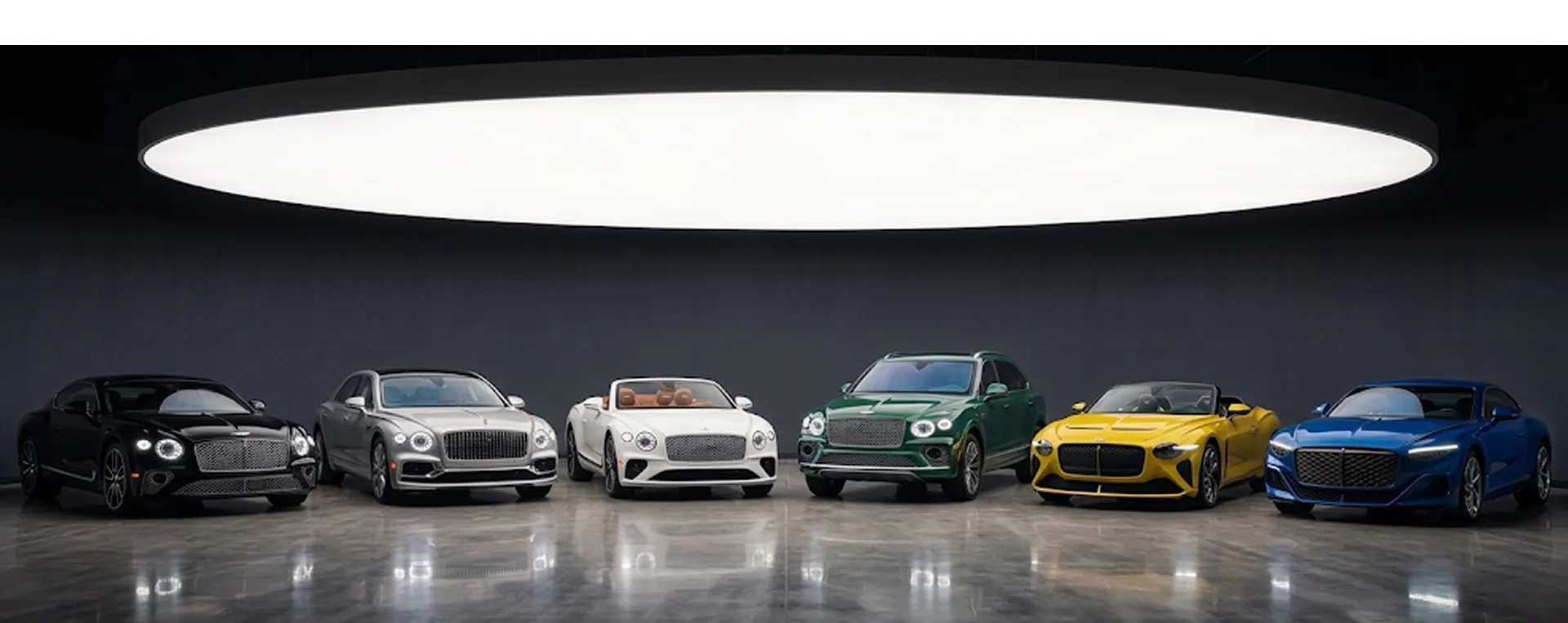 Seven Bentleys in black, silver, white, green, yellow and blue lined up beneath a showroom light