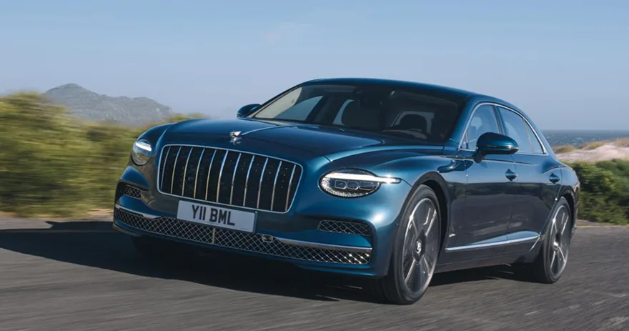 Blue Bentley Flying Spur driving along a coastal road