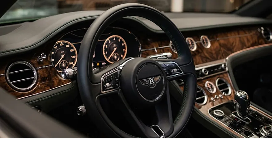 Bentley cockpit with its steering wheel, chrome dials and wood veneer dashboard