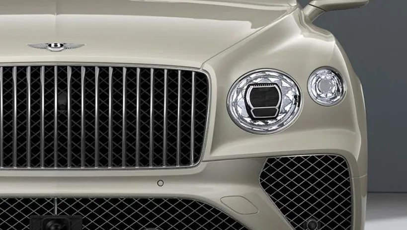 Front detail of a cream Bentley Bentayga showing its matrix grille and round headlights