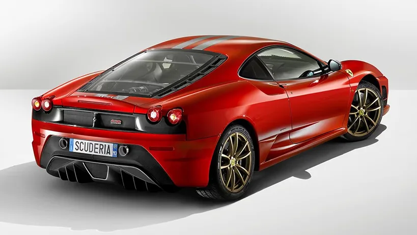 Rear three-quarter studio view of a red Ferrari F430 Scuderia on gold wheels