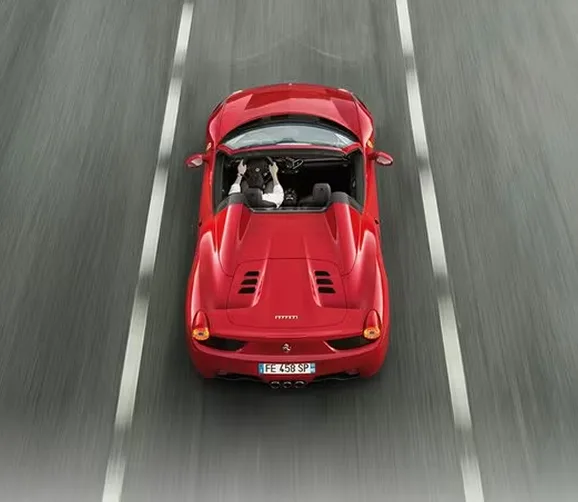 Overhead view of a red Ferrari 458 Spider tracking down a lane-marked road