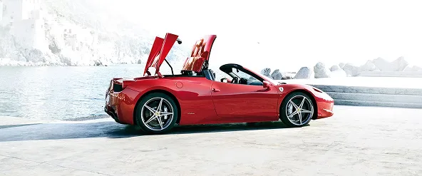 Red Ferrari 458 Spider with both doors open parked on a snow-covered lakeside road