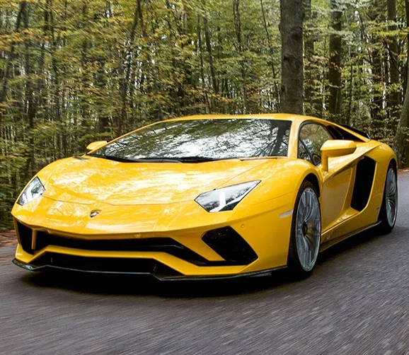 Yellow Lamborghini Aventador S driving along a tree-lined road